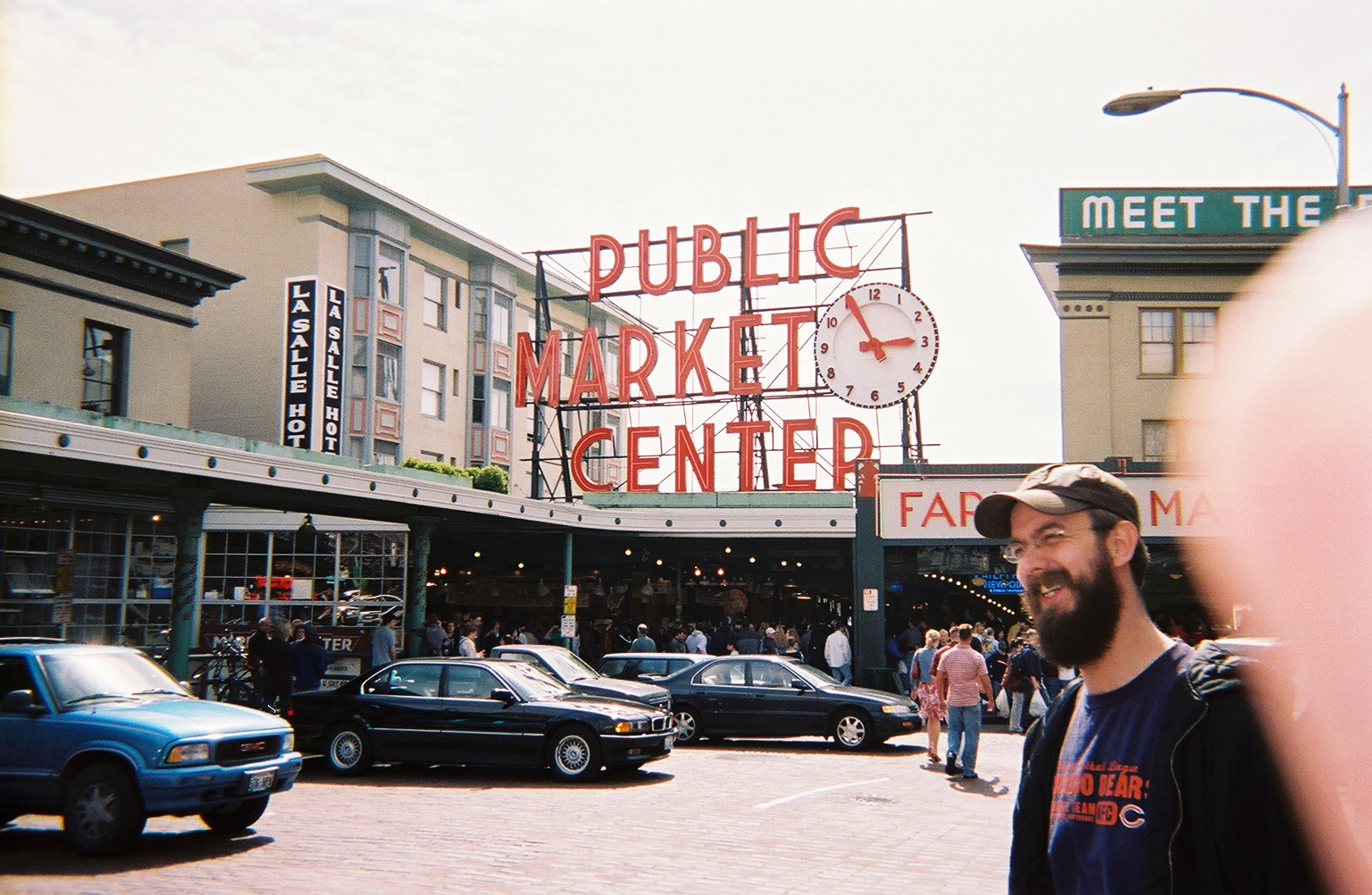 A man with a beard smiles in front of Seattle's Public Market Center